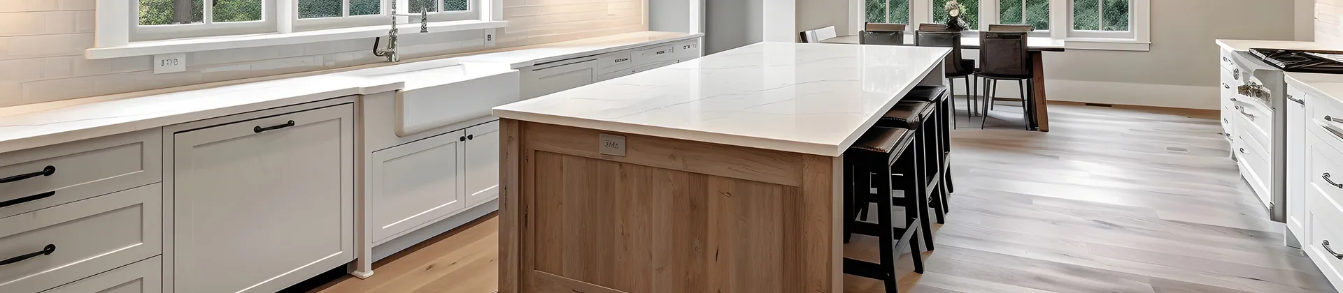 Spacious modern kitchen with white cabinetry, large marble island, farmhouse sink, and natural wood accents