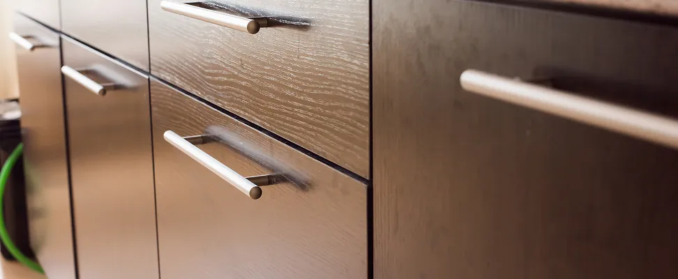 Close-up of dark wood cabinets with brushed metal handles, highlighting the smooth texture and modern custom design